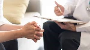 person with folded hands and doctor with clipboard and pen