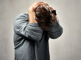 A man with his head between his elbows and his hands behind his head.